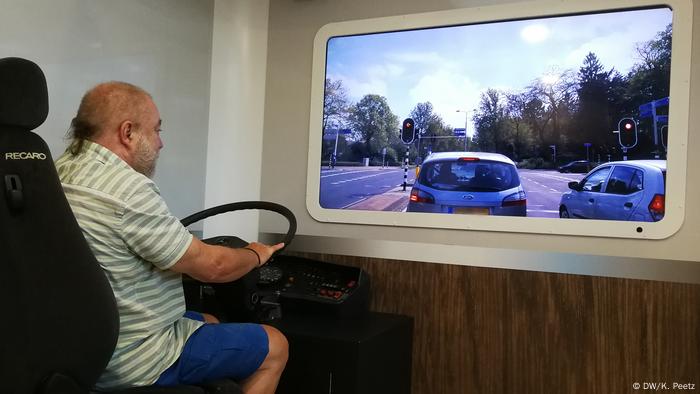 Rudi sitzt am Steuer der Bus-Attrappe. Vor ihm ist das Video von der Straße durch Doetinchem zu sehen.
