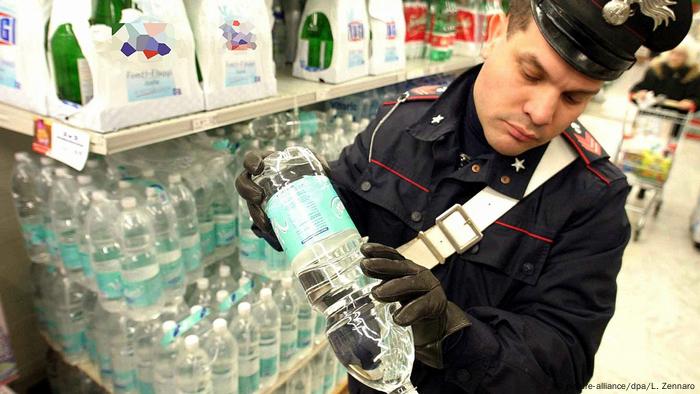 An Italian police officer inspects a bottle of mineral water in Genoa, Italy in December 2003 (picture-alliance/dpa/L. Zennaro)