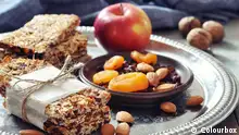 Granola bars on plate with nuts and dried fruits on wooden background