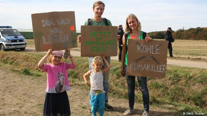 Eine Familie hält am Hambacher Forst Protestplakate hoch (Foto: DW/G. Rueter )