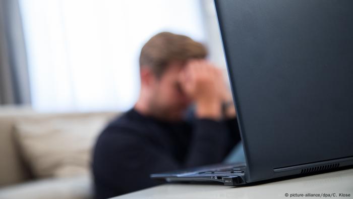 Hombre agobiado tras un laptop.