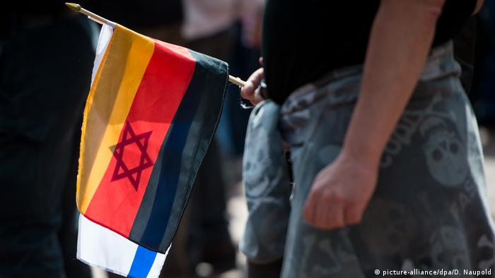 Сторонник движения Pegida держит в руке флаги Израиля и Германии 