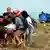 Skupina ljudi nosi ozlijeđenog dalje od plaže
