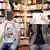 Two men sit in a bookstore, one with an e-reader obscuring his face, the other holding a German book in front of his face. 