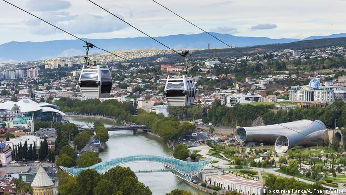 A gondola above the Mtkvari River shows Tbilisi in the backdrop