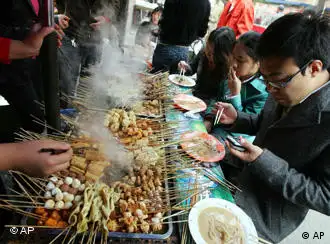A man checks his mobile phone while eating at a food stall in Beijing Wednesday Oct. 24, 2007. Questions about the quality of Chinese toys, food and other goods have grown in recent months after a string of product recalls and import bans. (AP Photo/Greg Baker)