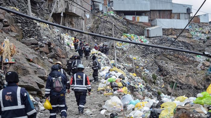 Miners walking up hilllside amid garbage