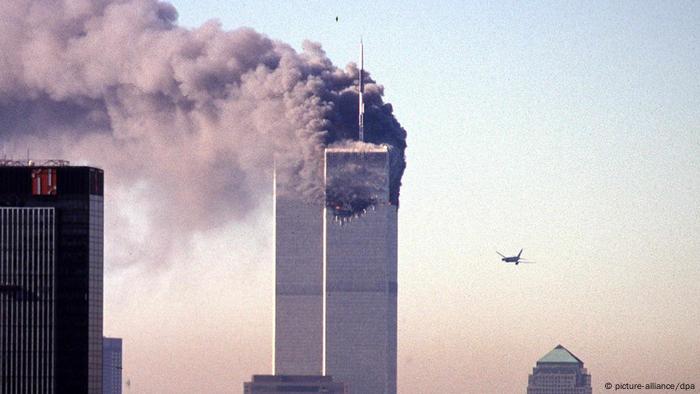 a plane flies towards a smoking skyscrapper (picture-alliance/dpa)