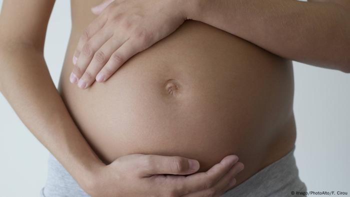 Kobieta w ciąży trzymająca się za brzuch