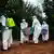 Health workers in protective clothing carry a casket with the body of someone suspected of having died of Ebola to a truck outside a house
