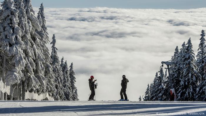 Two skiers stand on a slope