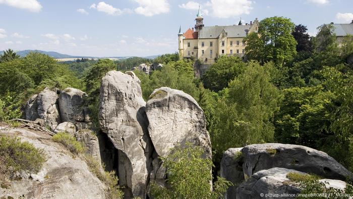 Hruba Skala Castle, with rugged sandstone cliffs in the foreground