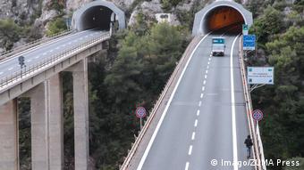 A migrant walks along a highway to a tunnel that separate France from Italy