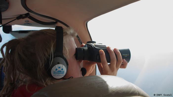 An NGO worker scanning the sea from a plane