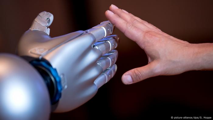 Eine menschliche Hand und eine Roboterhand berühren sich an den Fingern (Foto: Picture Alliance)