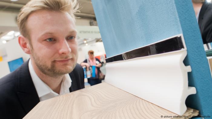 Ein Mann schaut sich das Modell einer Bodenfußleiste an (Foto: Picture Alliance)