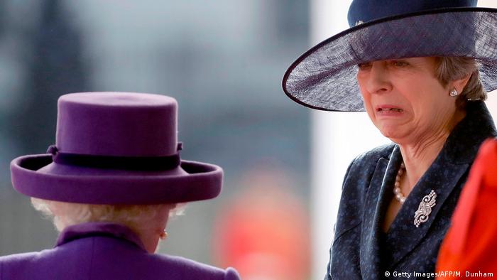 Former British Prime Minister Theresa May (R) reacts as she is greeted by Britain's Queen Elizabeth II (C), a look of disgust on her face, at a ceremony in 2018