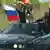 На автомобиле едут люди, в руках у них флаги Южной Осетии и России