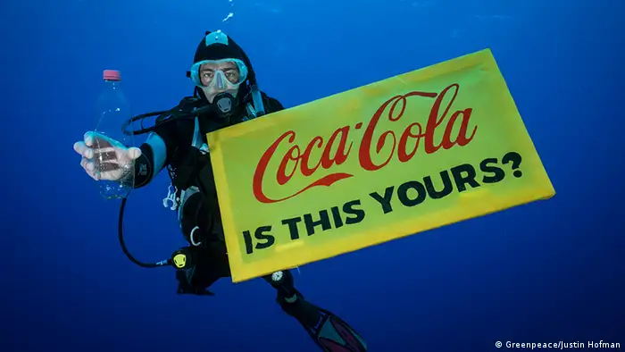 Ein Greenpeace-Taucher hält eine Leere Plastikfalsche und ein Schild mit der Aufschrift: Coca-Cola is this yours? - Coca-Cola, gehört das dir?