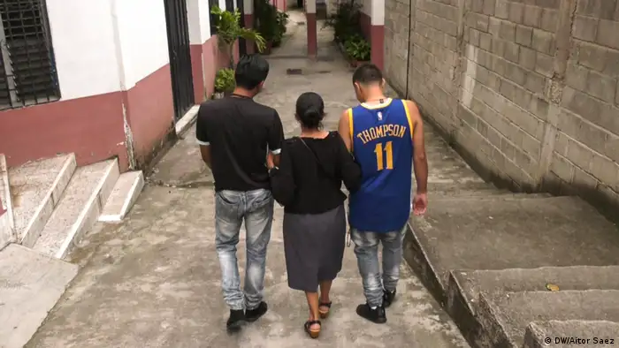 Dos hombres y una mujer caminan por un callejuela. (DW/Aitor Saez)