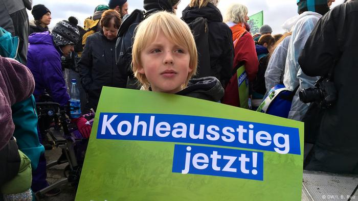 En una protesta masiva contra el carbón en el oeste de Alemania, un niño de nueve años sostiene una pancarta que dice ¡Salga del carbón ahora! 