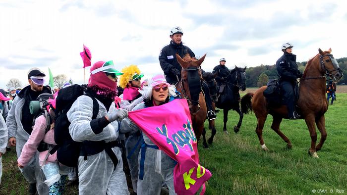 Los policías a caballo siguen de cerca a los manifestantes vestidos con alas y trajes de protección blancos.