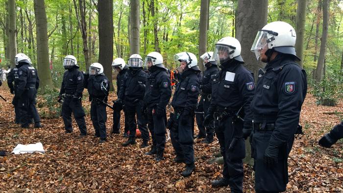 Los agentes de policía construyen una barrera dentro del bosque durante una protesta masiva contra el carbón en el oeste de Alemania.  Impiden que manifestantes vayan en esa dirección