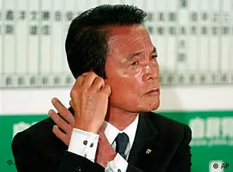 Prime Minister Taro Aso, leader of the Liberal Democratic Party, adjusts a earpiece during a TV interview while observing the result of the parliamentary elections ballot counting at the party headquarters in Tokyo Sunday, Aug. 30, 2009. Aso conceded defeat in elections Sunday as media exit polls indicated the opposition had won by a landslide, sending the conservatives out of power after 54 years of nearly unbroken rule amid widespread economic anxiety and desire for change. (AP Photo/Shuji Kajiyama)