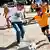 Slika prikazuje Filipa Lama kako igra fudbal sa decom u južnoafričkoj republici