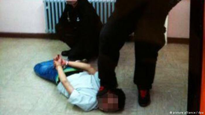 Deux gardes de sécurité maltraitant un homme allongé sur le sol