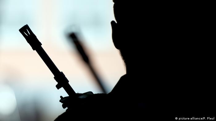 A back-lit person with a rifle
