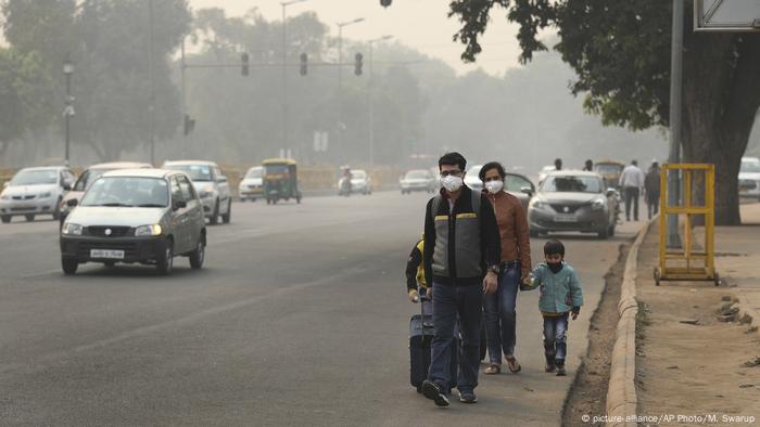 A family wears pollution masks and walk looking for a transportation a day after Diwali festival, in New Delhi (picture-alliance/AP Photo/M. Swarup)