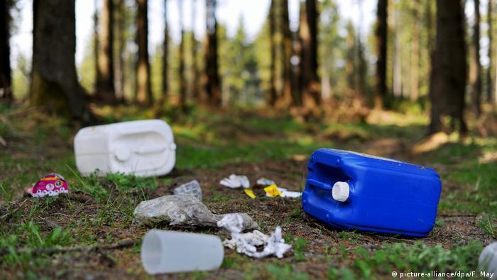 Envases de plástico, vasos y envoltorios de caramelos tirados en el bosque.