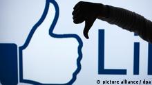 FILE - ILLUSTRATION - A woman makes the 'thumbs down' sign with her fist and thumb in front of an enlarged 'Like' symbol of the social netweorking site Facebook in Schwerin, Germany, 04 April 2013 (STAGED PICTURE). Photo: Jens Buettner/dpa (zu dpa Zuckerberg: Facebook arbeitet an «Gefällt mir nicht»-Knopf vom 15.09.2015) +++(c) dpa - Bildfunk+++ | Verwendung weltweit