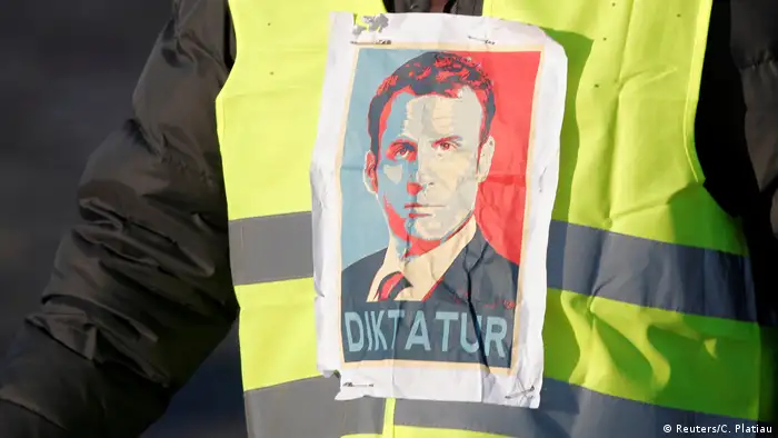 A yellow vest demonstrator has a picture of Macron on it with the word, 'dictator' under his face (Reuters/C. Platiau)