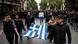 A group of demonstrators carries a Greek flag with carnations placed on it A group of demonstrators carries a Greek flag with carnations placed on it