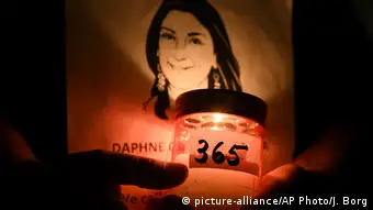 The light of a candle shines on a portrait of Daphne Caruana Galizia