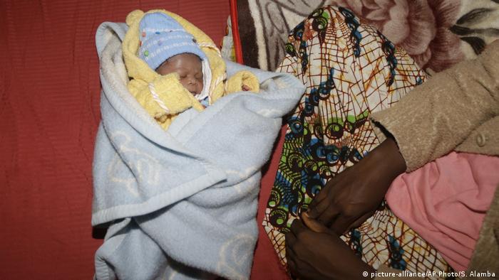 An Ebola survivor sits next to her newborn baby