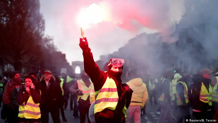 A yellow-vest protester holds up a flare on the Champs-Elysees (Reuters/B. Tessier)