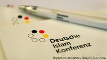 Pressemappen und ein Kugelschreiber mit der Aufschrift Deutsche Islam Konferenz liegen am 07.11.2016 während einer Tagung der Deutschen Islam Konferenz in Berlin auf einem Tisch. Thema der Konferenz war die muslimische Seelsorge in staatlichen Einrichtungen. Foto: Sebastian Gollnow/dpa | Verwendung weltweit