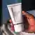 A hand holding a tube of skin lightening cream