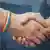 Two people holding hands, one with a rainbow bracelet, the other with a cross bracelet