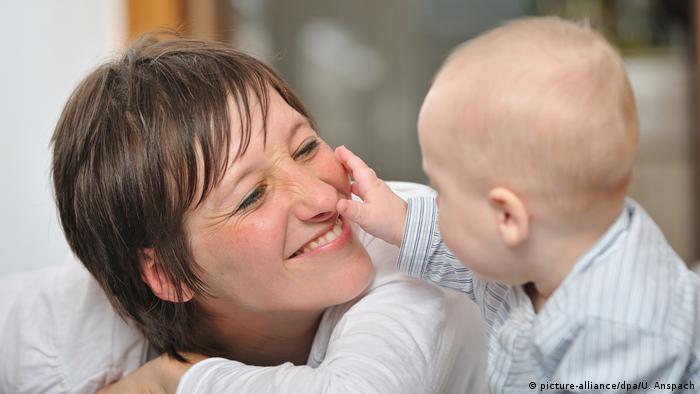 Ein Baby fasst die Nase einer Jungen Mutter an. 
