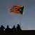 Silhouette of people with one person holding a Catalan independence flag