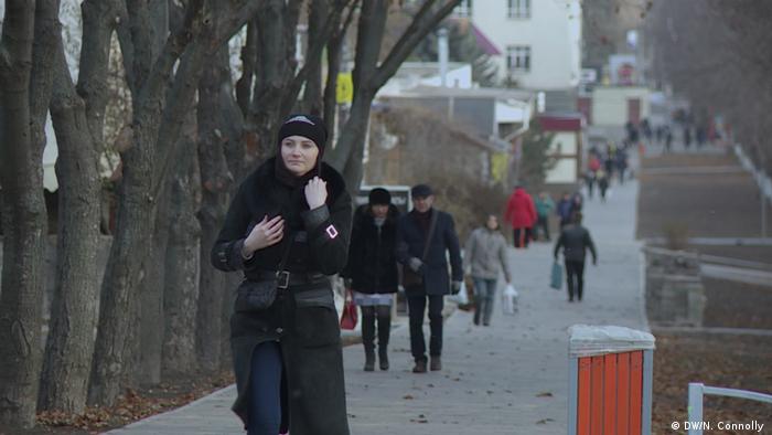 People walk along a sidewalk in Mariupol, Ukraine