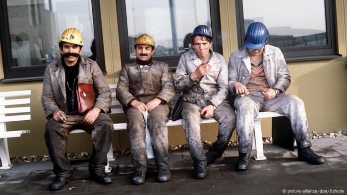 Miners, guest workers from Turkey, sit on a bench during a break at a mine in Germany