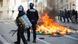 Riot police stand next to a bin fire Riot police stand next to a bin fire