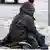 Beggar sitting on snowy sidewalk