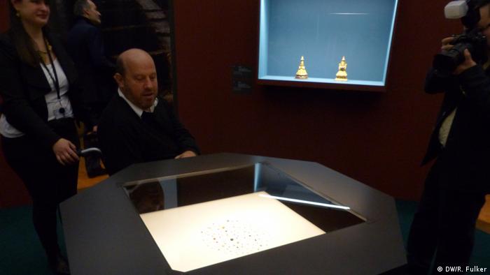 Luke Peppé sits in a wheelchair and views the exhibit of tiny stones in a glass case (DW/R. Fulker)