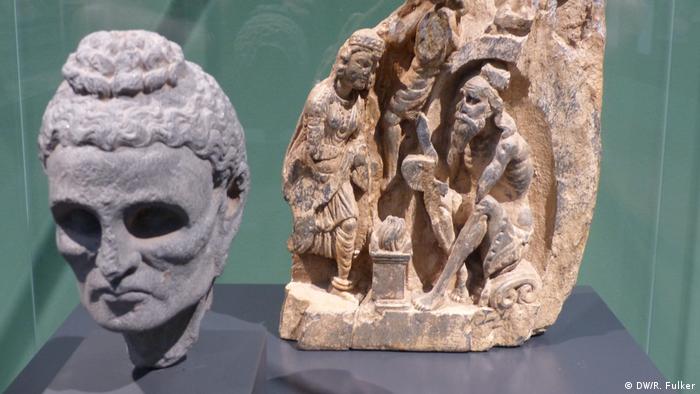 Two objects: 1) a stone depiction of the Buddha with a bird nest on his head, and 2) another one showing an emaciated man begging for food (DW/R. Fulker)